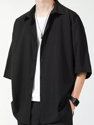 Men's black oversized short sleeve button-up shirt with a white t-shirt underneath.