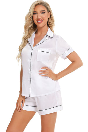 White satin pajama set with black piping, button front top and shorts.