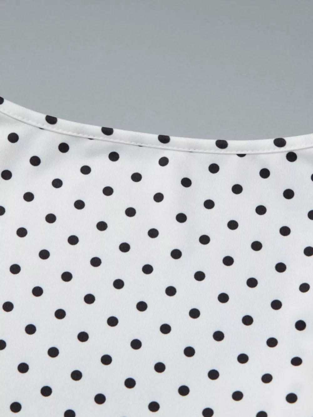 White t-shirt with black polka dots and a ruched detail at the neckline.
