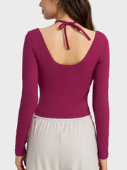 Ribbed long sleeve active top in magenta with cutout shoulders and halter tie detail.