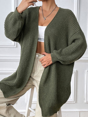 Olive green ribbed knit cardigan with balloon sleeves and a V-neck, styled open over a white top.