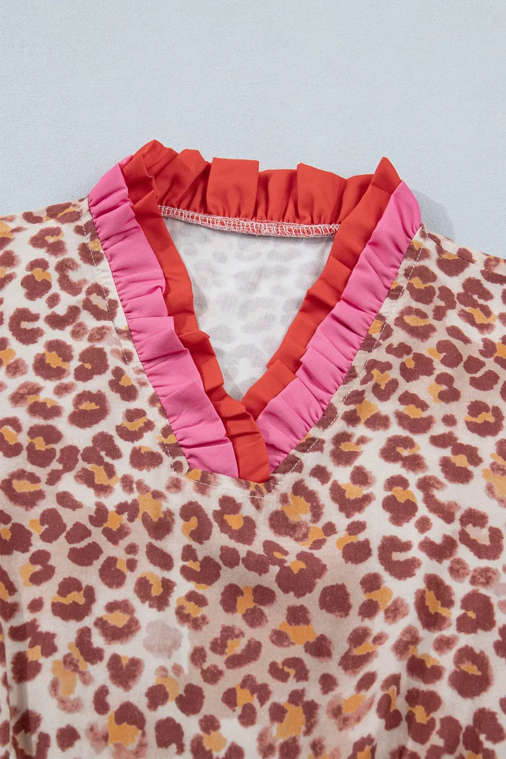 Leopard print V-neck dress with pink and coral ruffled trim detail.