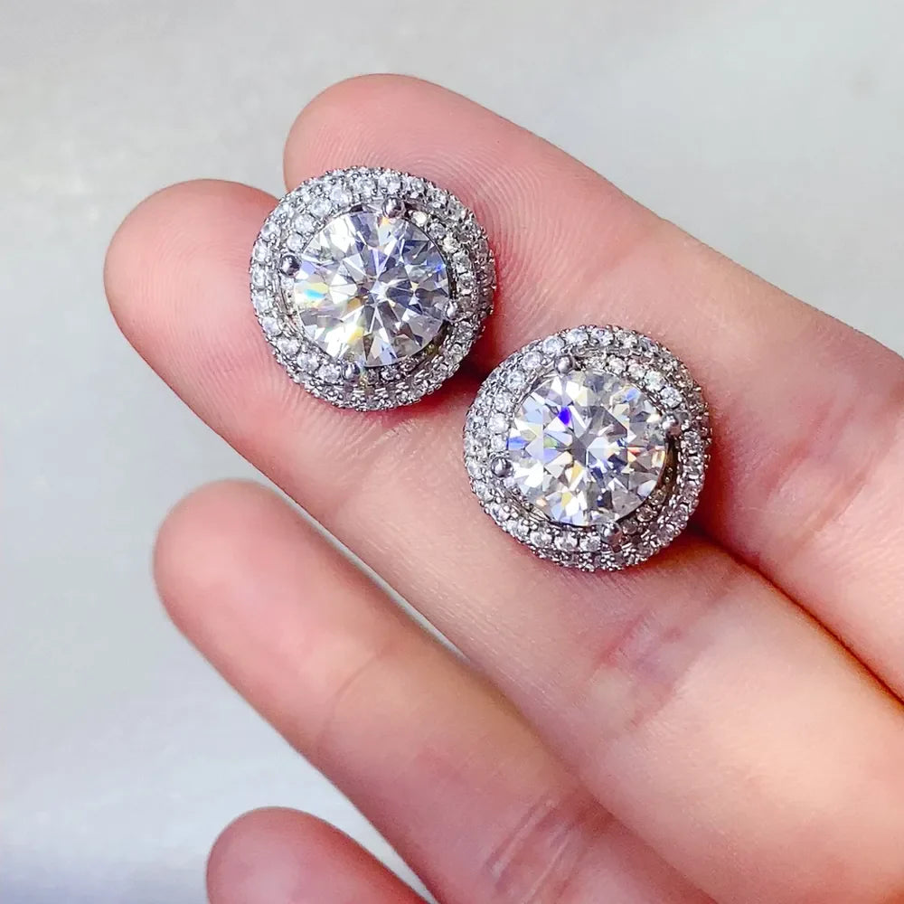 Halo diamond cluster stud earrings in silver with a central stone surrounded by smaller stones.