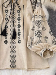 Apricot embroidered tie neck blouse with tassels and puff sleeves.