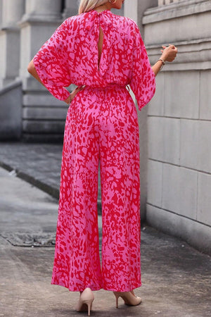 Crimson splatter tie-waist palazzo jumpsuit in hot pink with wide legs and open back detail.
