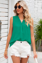 Green textured sleeveless blouse with V-neck and front pleats, styled with white shorts.