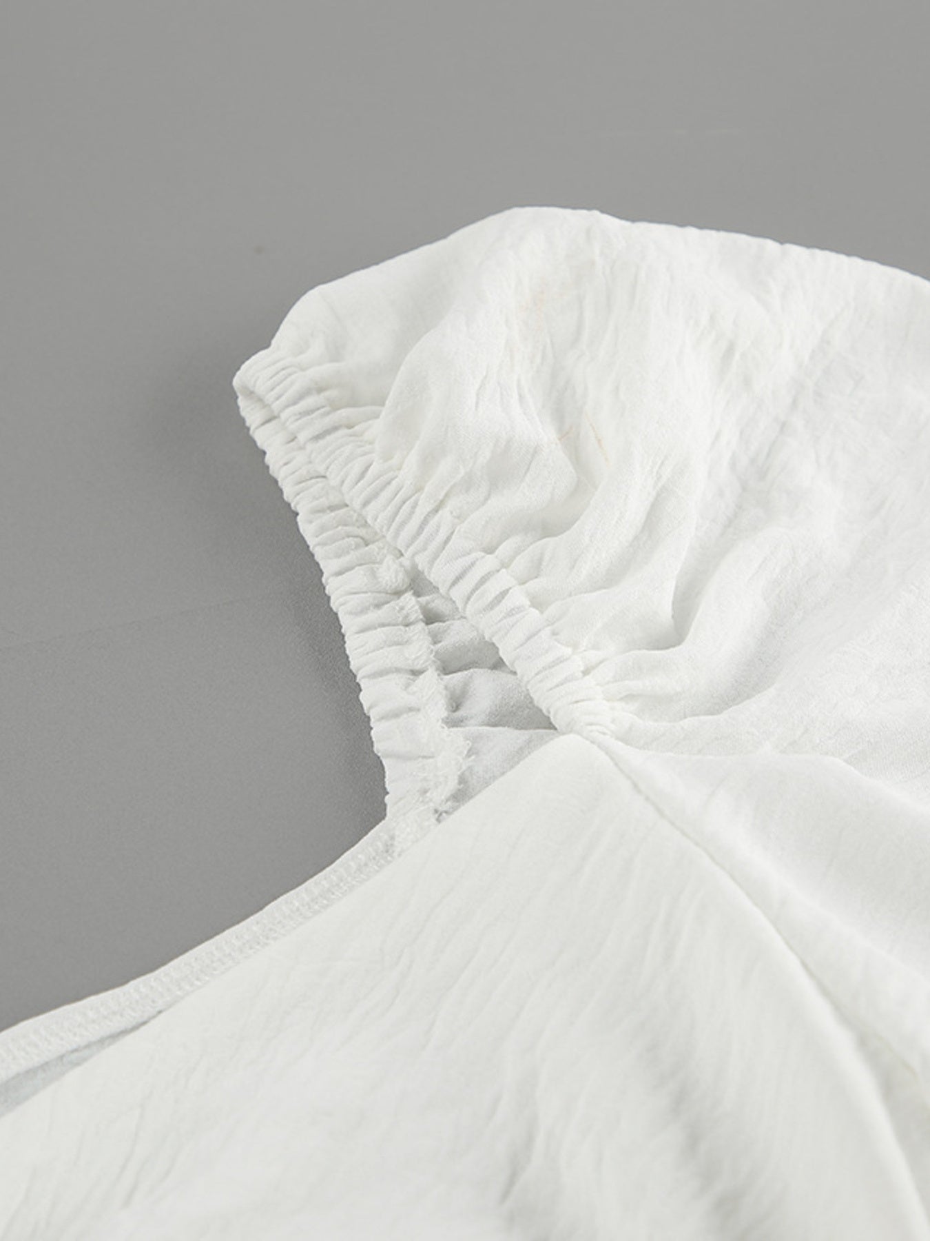 White off-shoulder midi dress with ruched neckline detail and textured fabric.