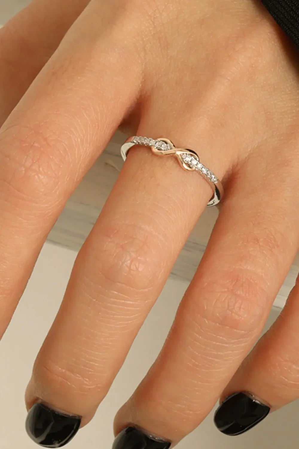 Eternity knot ring with pavé stones in silver and rose gold tones.