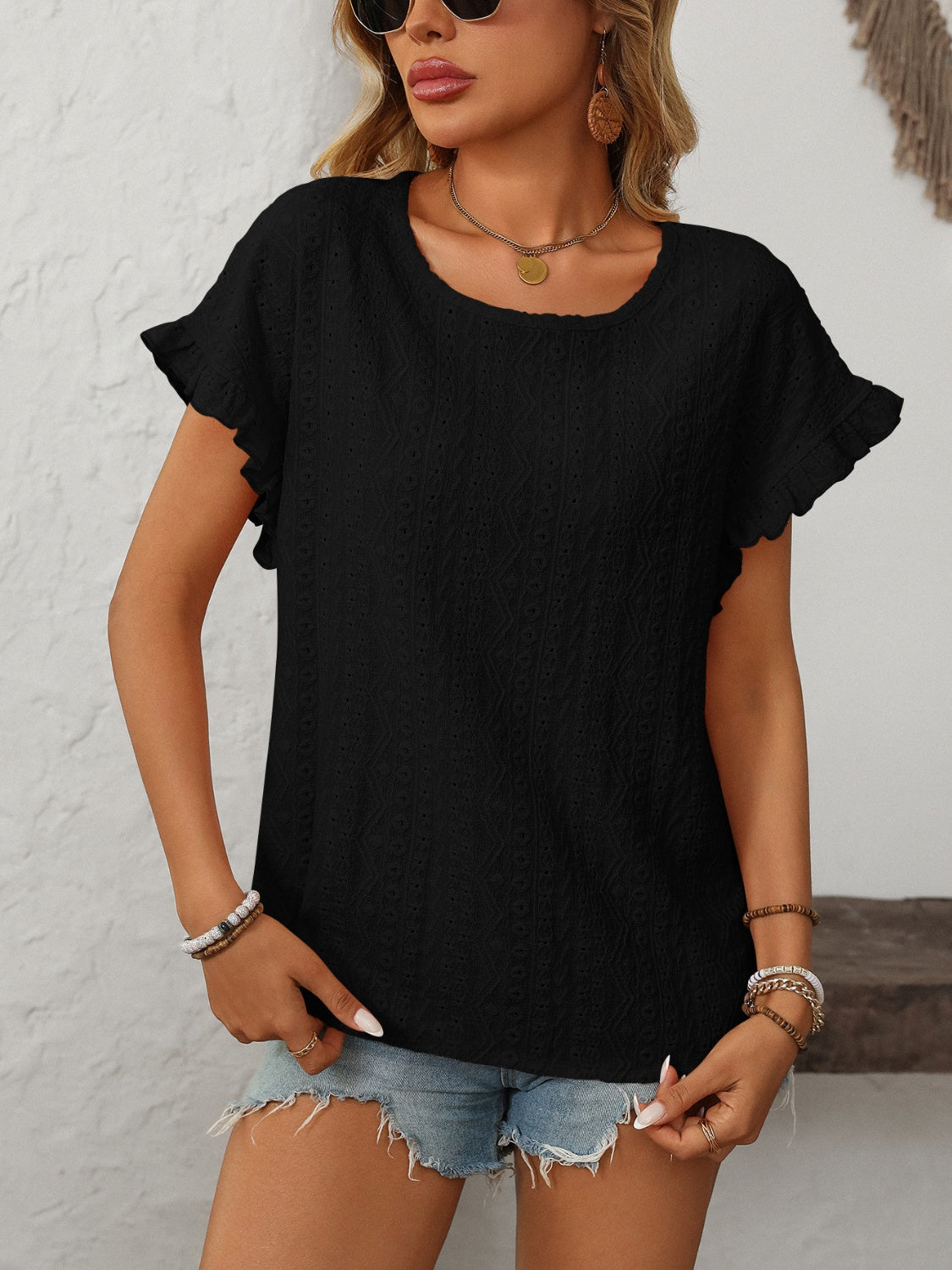 Black eyelet knit blouse with ruffled short sleeves and a scoop neckline.