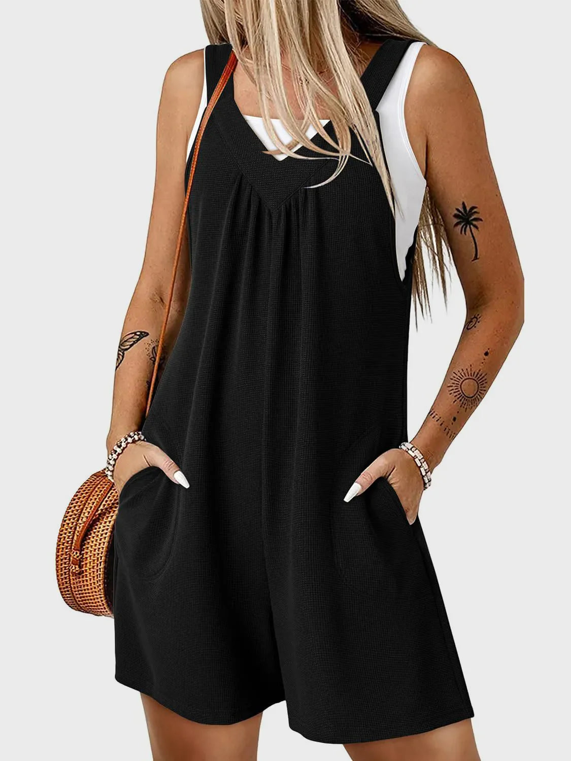 Black textured romper with gathered yoke and pockets, styled with a white tank top.