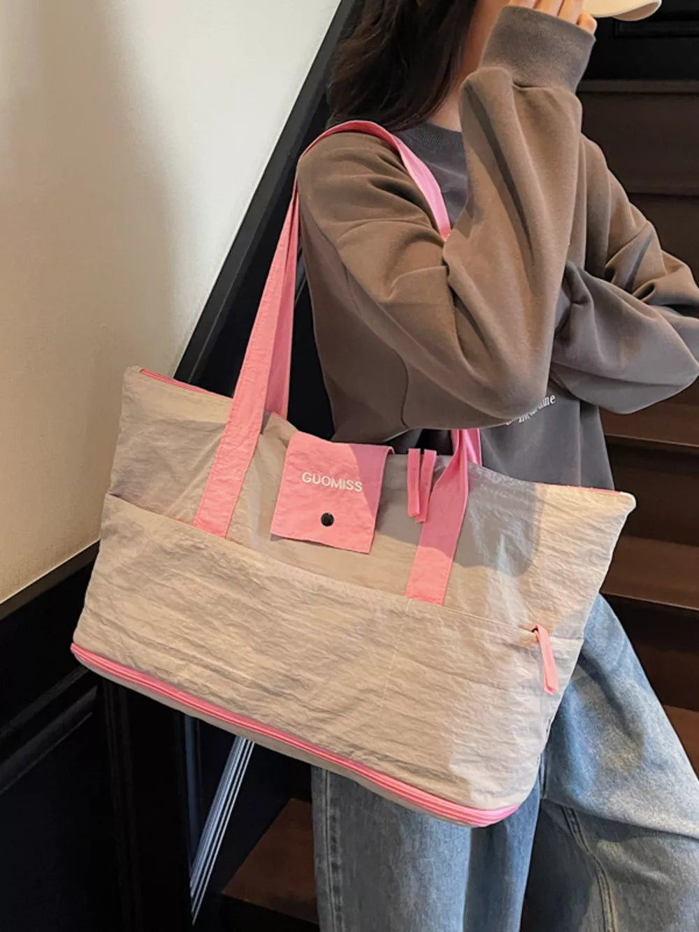 Grey nylon travel bag with pink trim and handles, featuring a small front pocket.