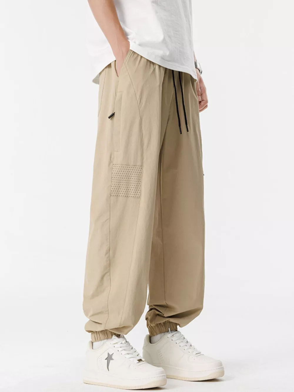 Khaki jogger sweatpants with drawstring and perforated detail on leg