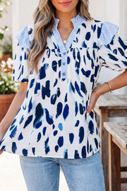 Vibrant abstract print polyester shirt with ruffled V-neck and button detail.