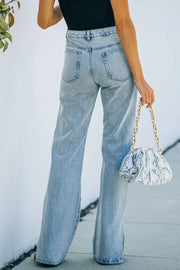Light wash denim flared hem trousers with side slits, shown from the back.