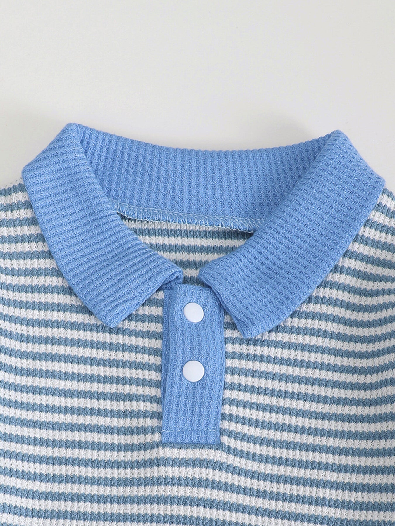 Children's blue and white striped polo shirt with waffle knit texture and two white buttons.