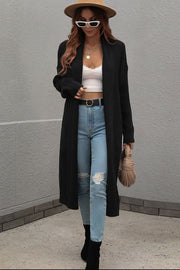 Black textured knit maxi cardigan with open front and long sleeves, styled with jeans and a white top.