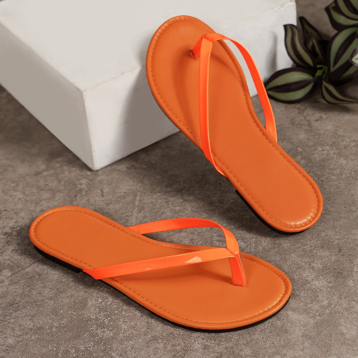Orange minimalist toe-post sandals with thin straps.