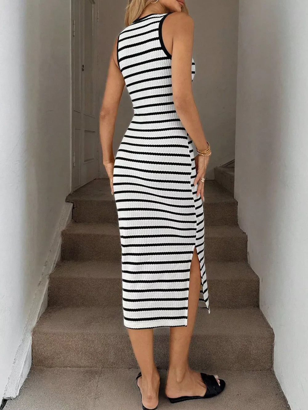 Sleek black and white striped bodycon midi dress with a high slit and sleeveless design.