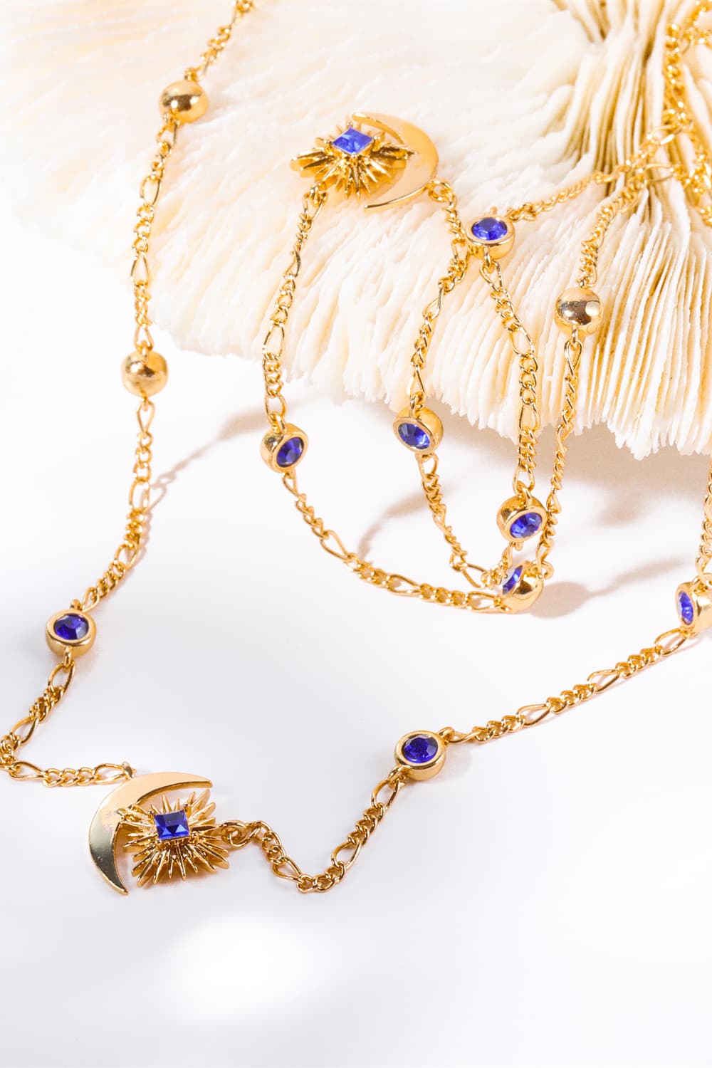 Gold celestial necklace with sunburst, crescent moon, and blue gems.