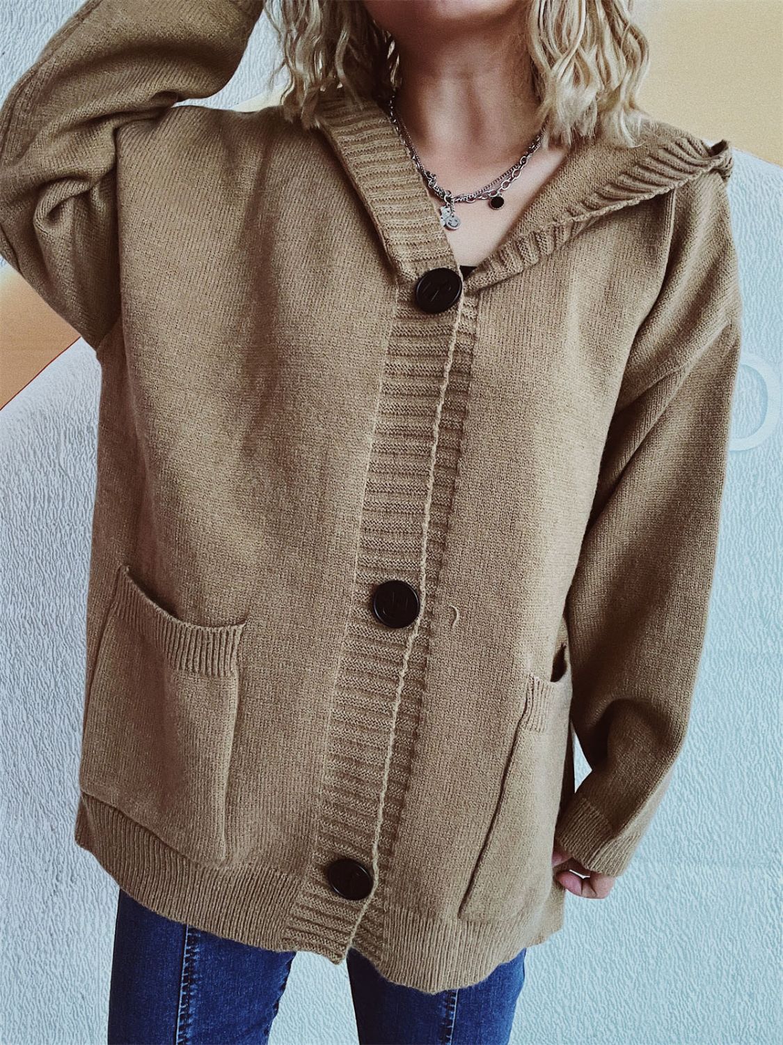 Taupe chunky knit hooded button-down cardigan with pockets and black buttons.