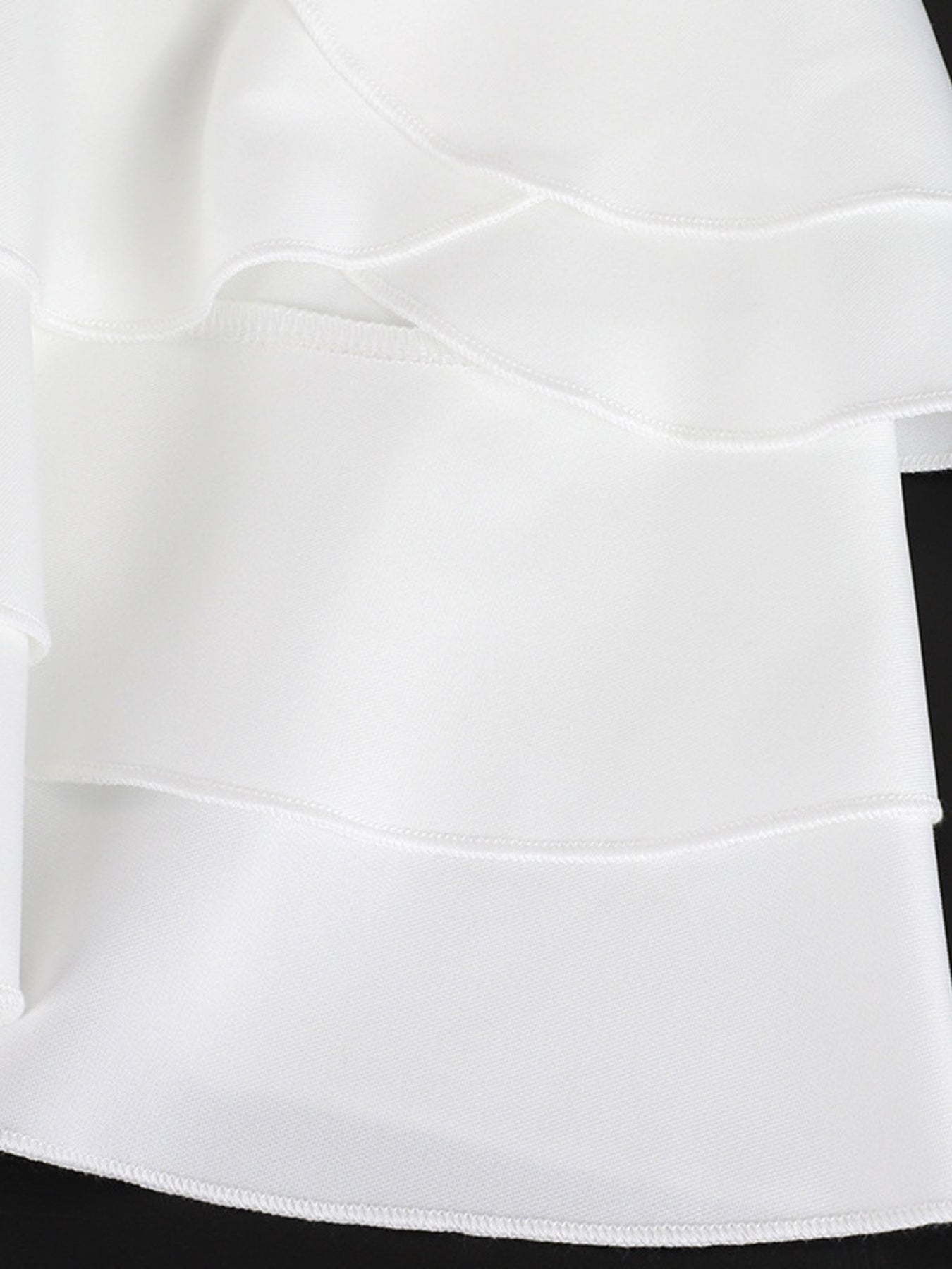 White tiered ruffled mini dress with a fitted bodice and elegant details.
