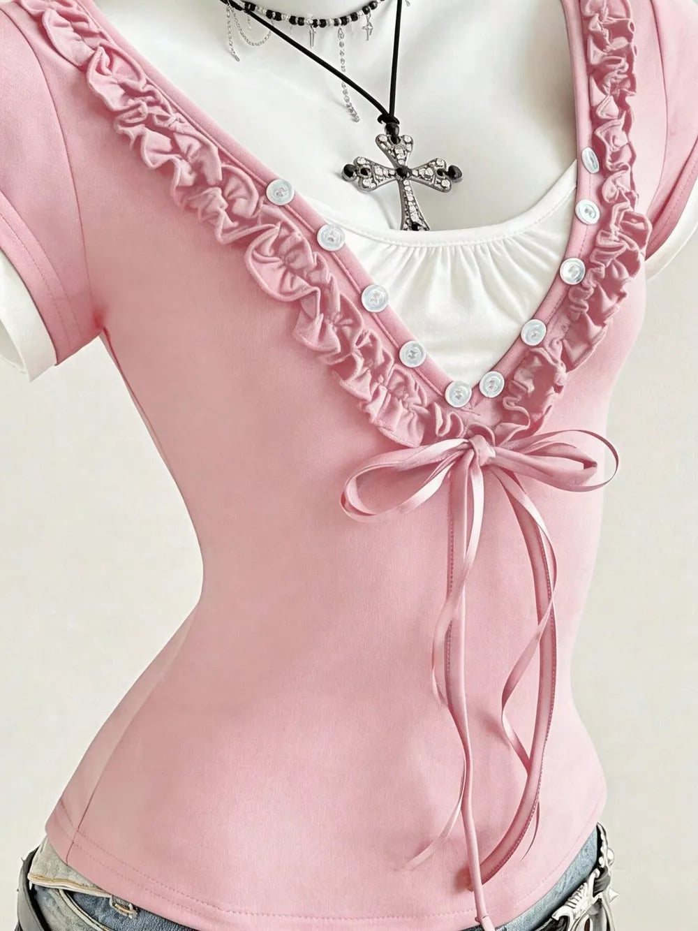 Pink maternity t-shirt with ruffled neckline, white buttons, and a satin bow detail.