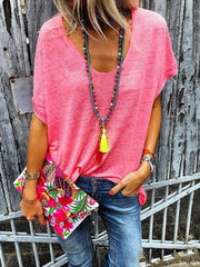 Relaxed V-neck tee in pink with dolman sleeves, styled with jeans and a colorful clutch.