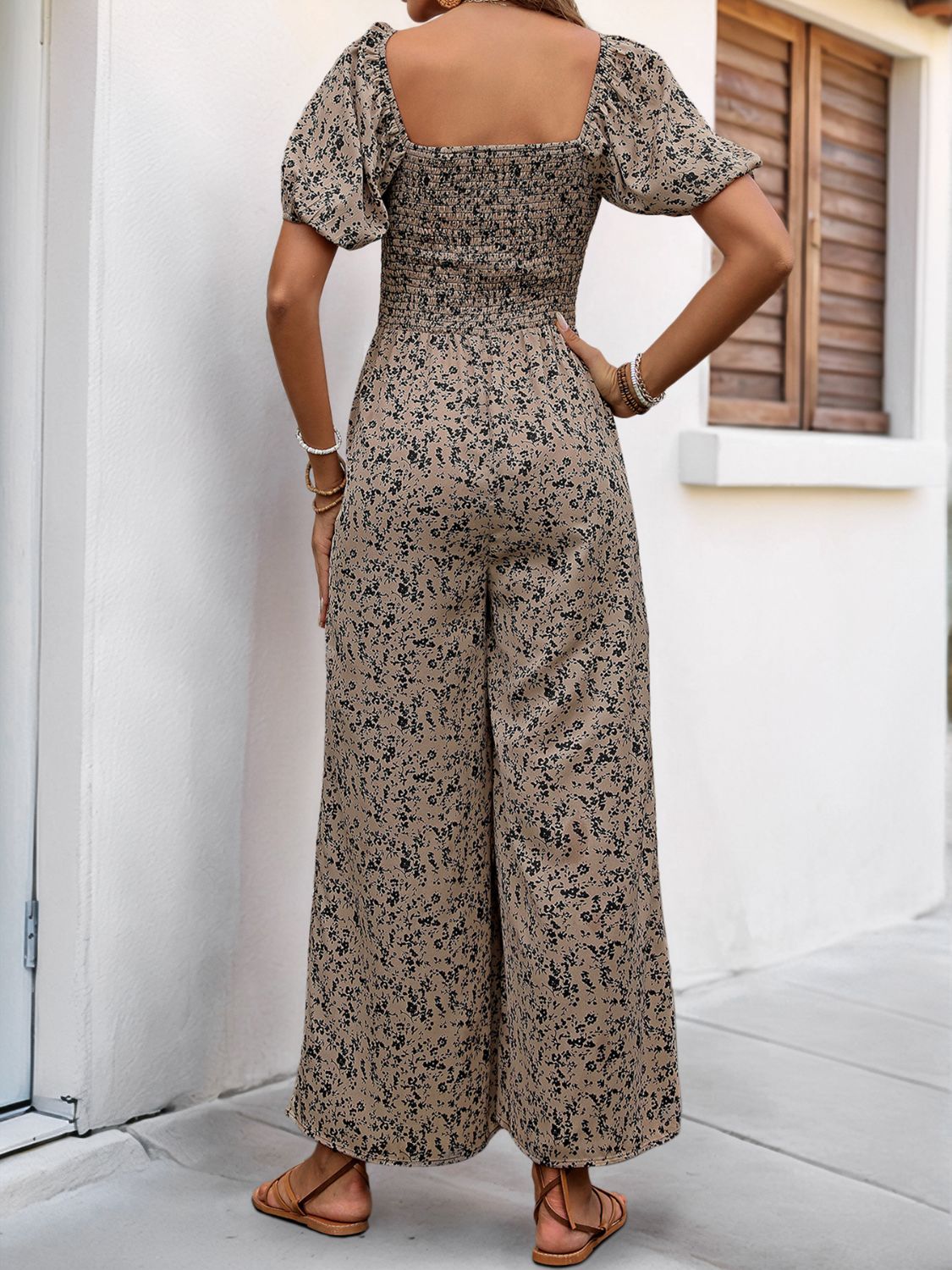 Taupe floral smocked bodice jumpsuit with puff sleeves and wide legs.