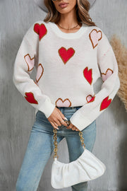White knit crewneck sweater with red and blush pink heart motifs, long sleeves.