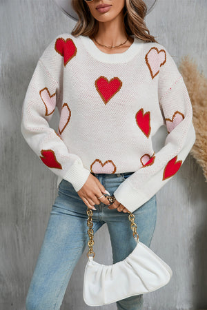 White knit crewneck sweater with red and blush pink heart motifs, long sleeves.