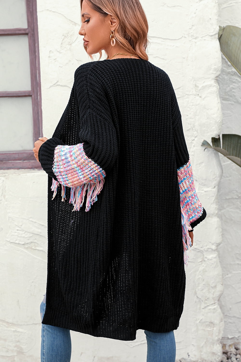 Black knit cardigan with textured sleeves featuring colorful fringe detail