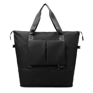 Black foldable travel tote with dual exterior pockets and top handles.