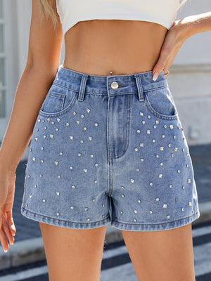 Medium wash denim cutoff shorts with allover stud embellishments