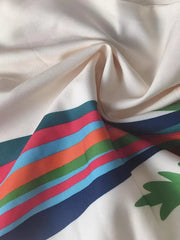 Maxi skirt fabric detail with colorful stripes and green leaf print on white.