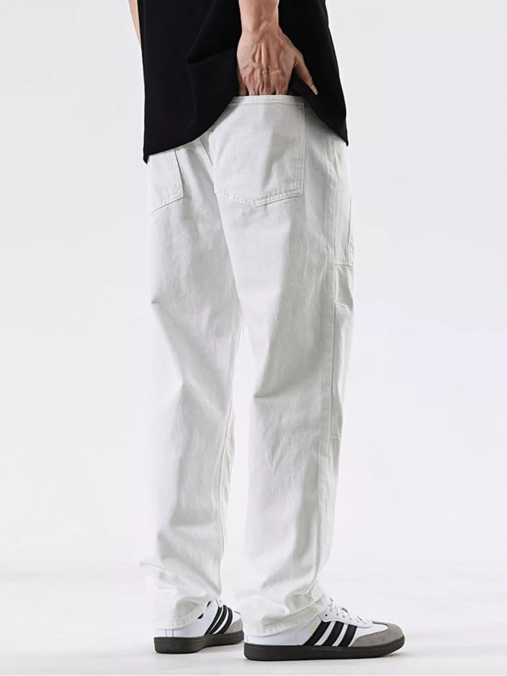 Men's white cotton jeans with pocket detail and relaxed fit.