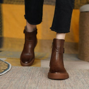 Brown leather ankle boots with round toe, platform sole, and decorative buckle detail.