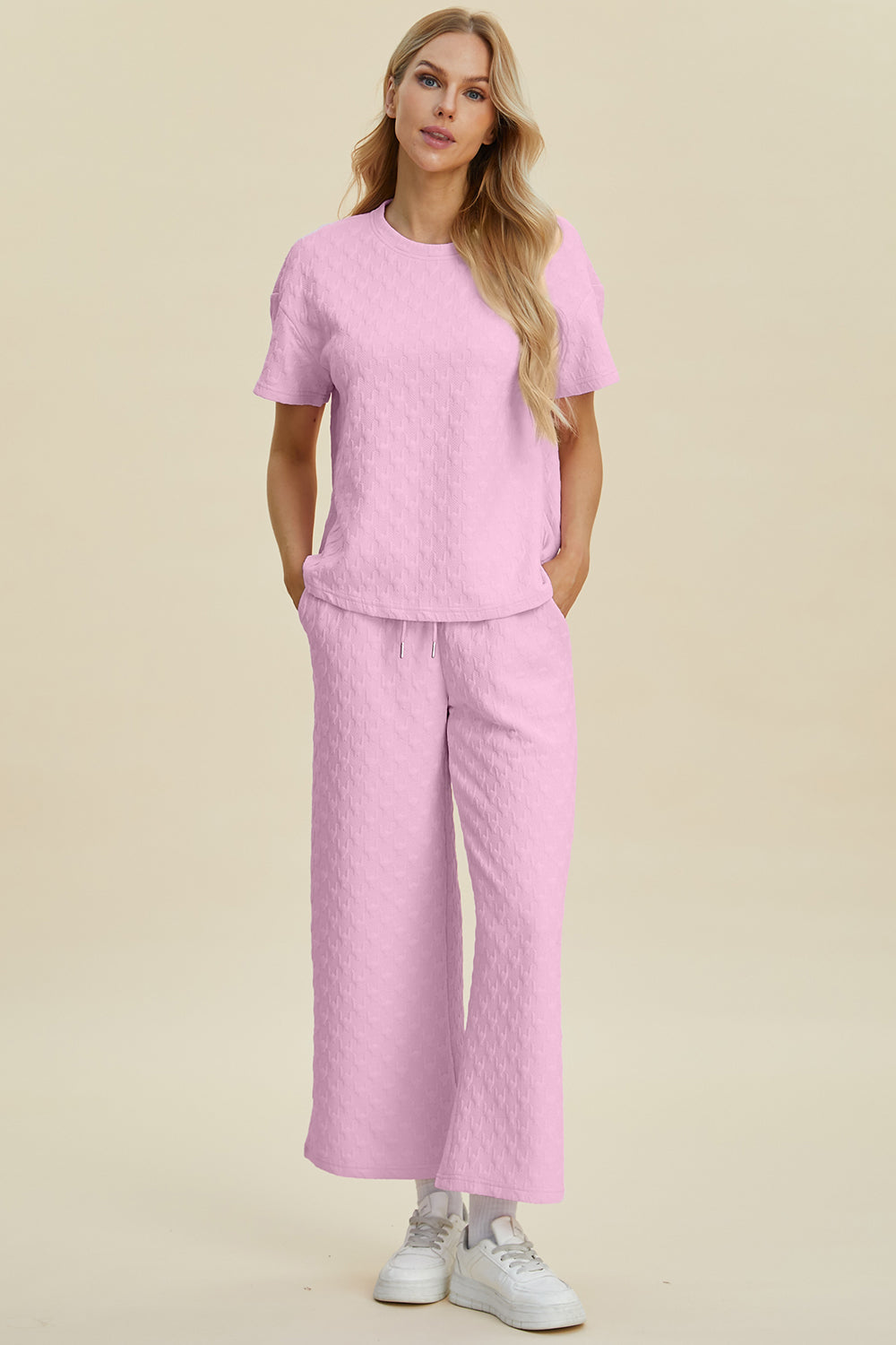 Pink textured knit lounge set with wide leg pants and short sleeve top.