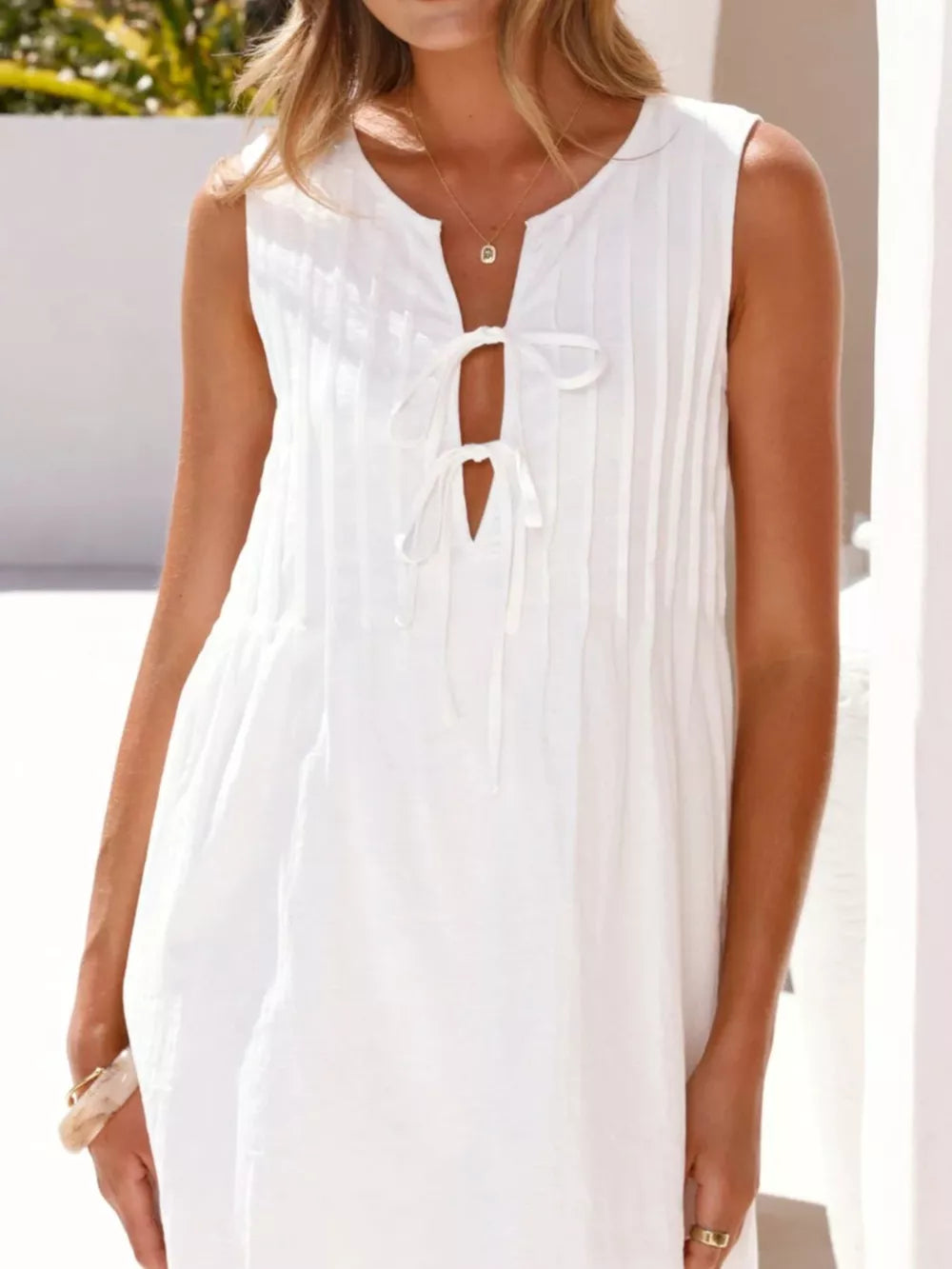 White tie-front mini dress with a keyhole neckline and subtle vertical pleats.
