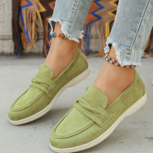 Green round toe slip-on loafers with decorative strap detail.