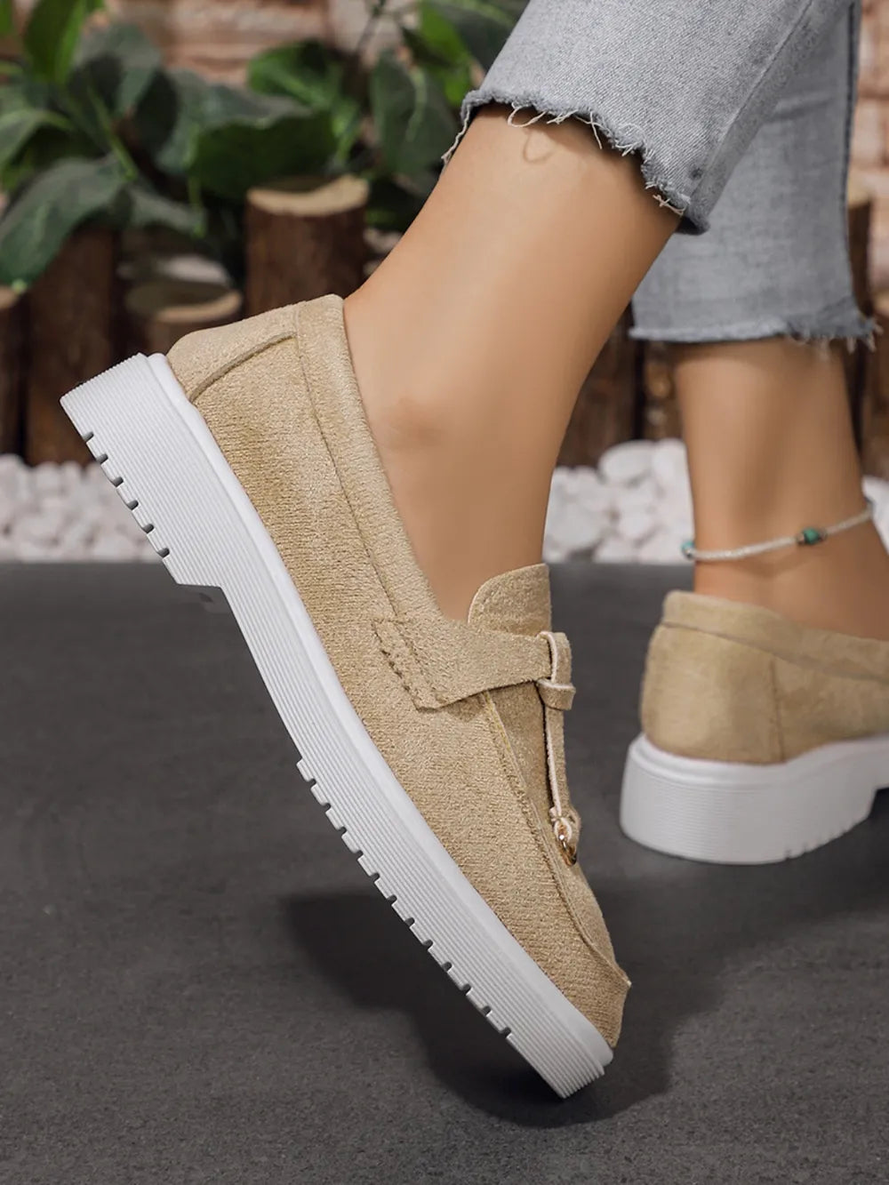 Beige suede loafer slides with tassel detail and white sole.
