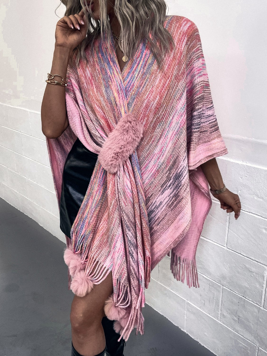 Pink knit wrap coat with multicolor stripes and faux fur pom-pom details.
