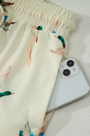 Beige pajama pants with mallard duck print and drawstring waist, showing a phone in the pocket.