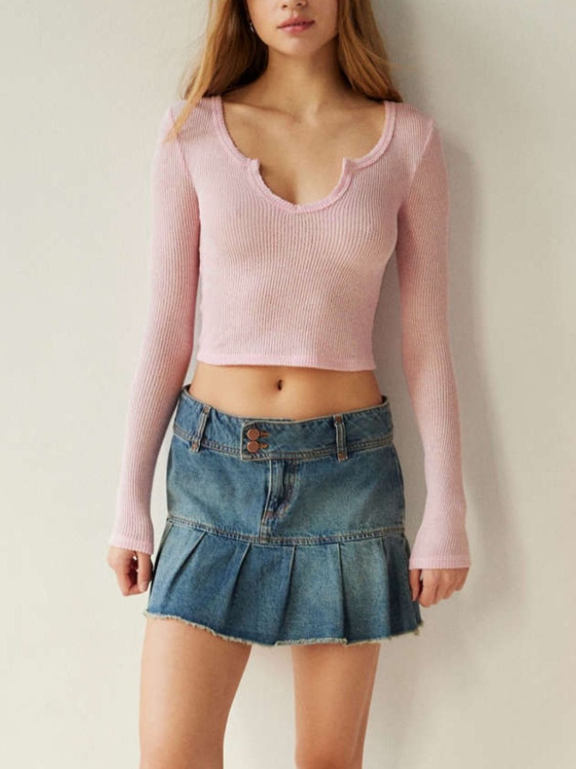 Dusty pink ribbed crop top with a notched neckline and long sleeves.