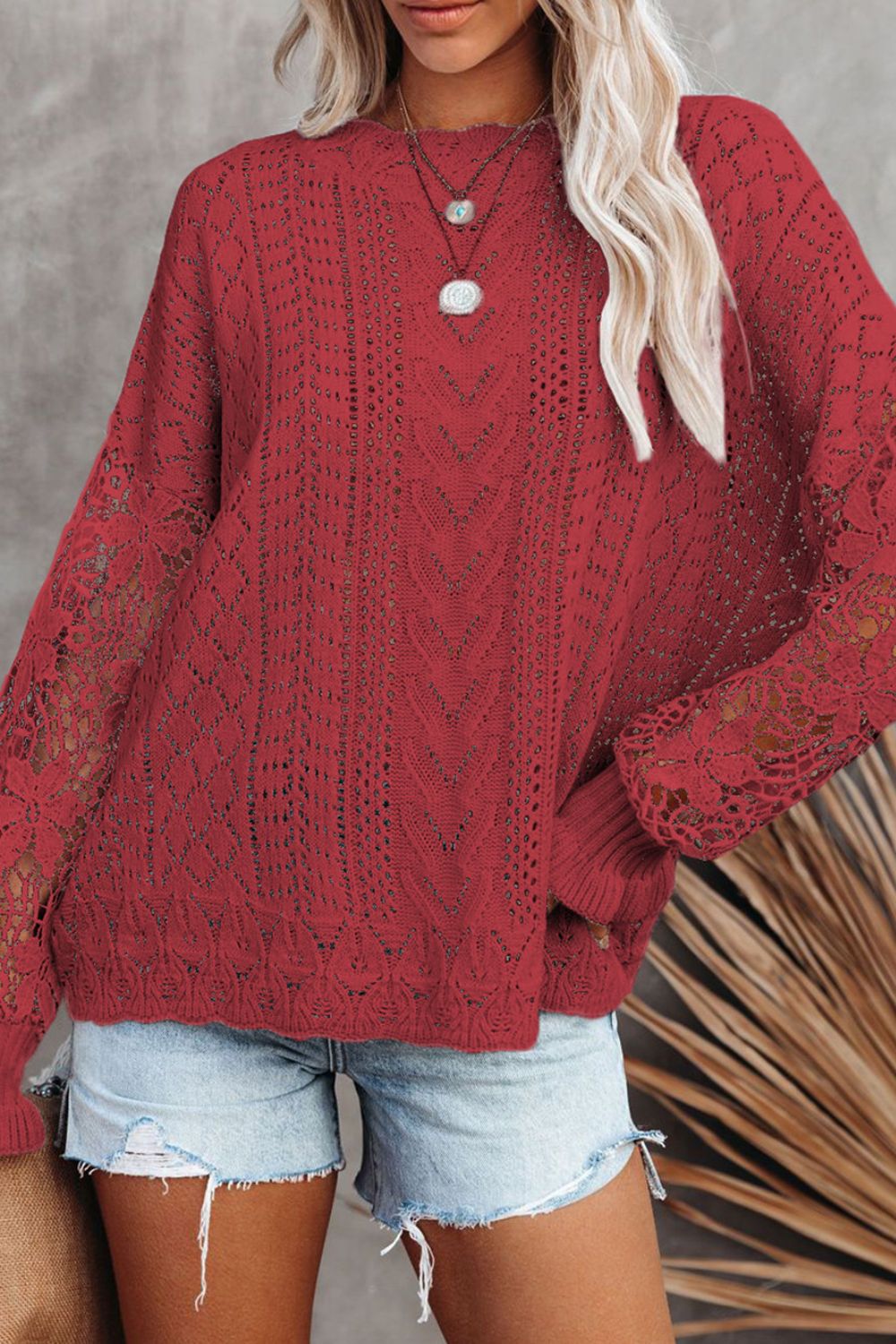Red openwork knit sweater with lace sleeves and a relaxed fit.
