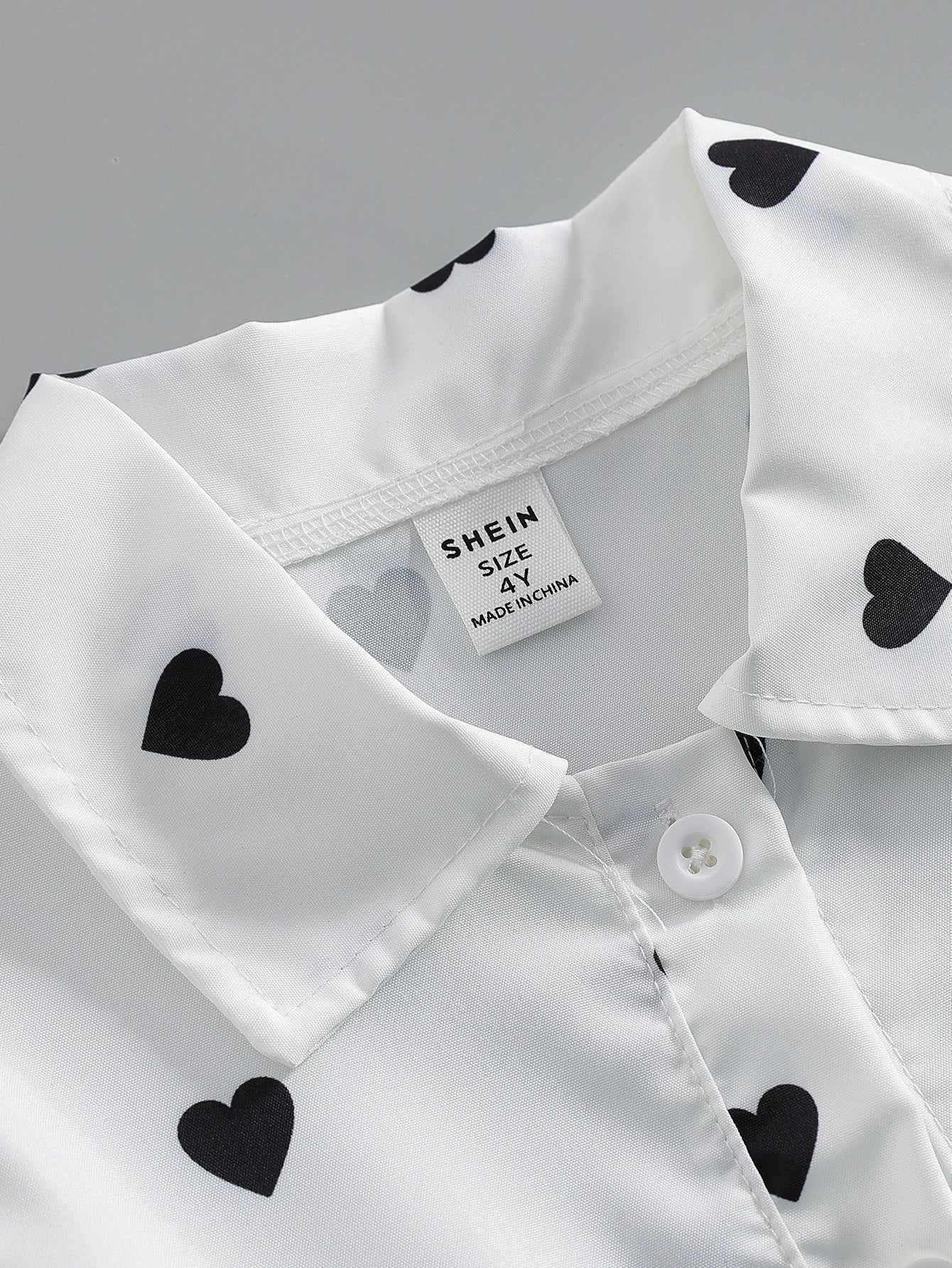 Baby dress with black heart print on white, button front detail.