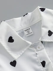 Baby dress with black heart print on white, button front detail.