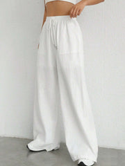 White linen wide-leg drawstring trousers with pockets, styled casually.