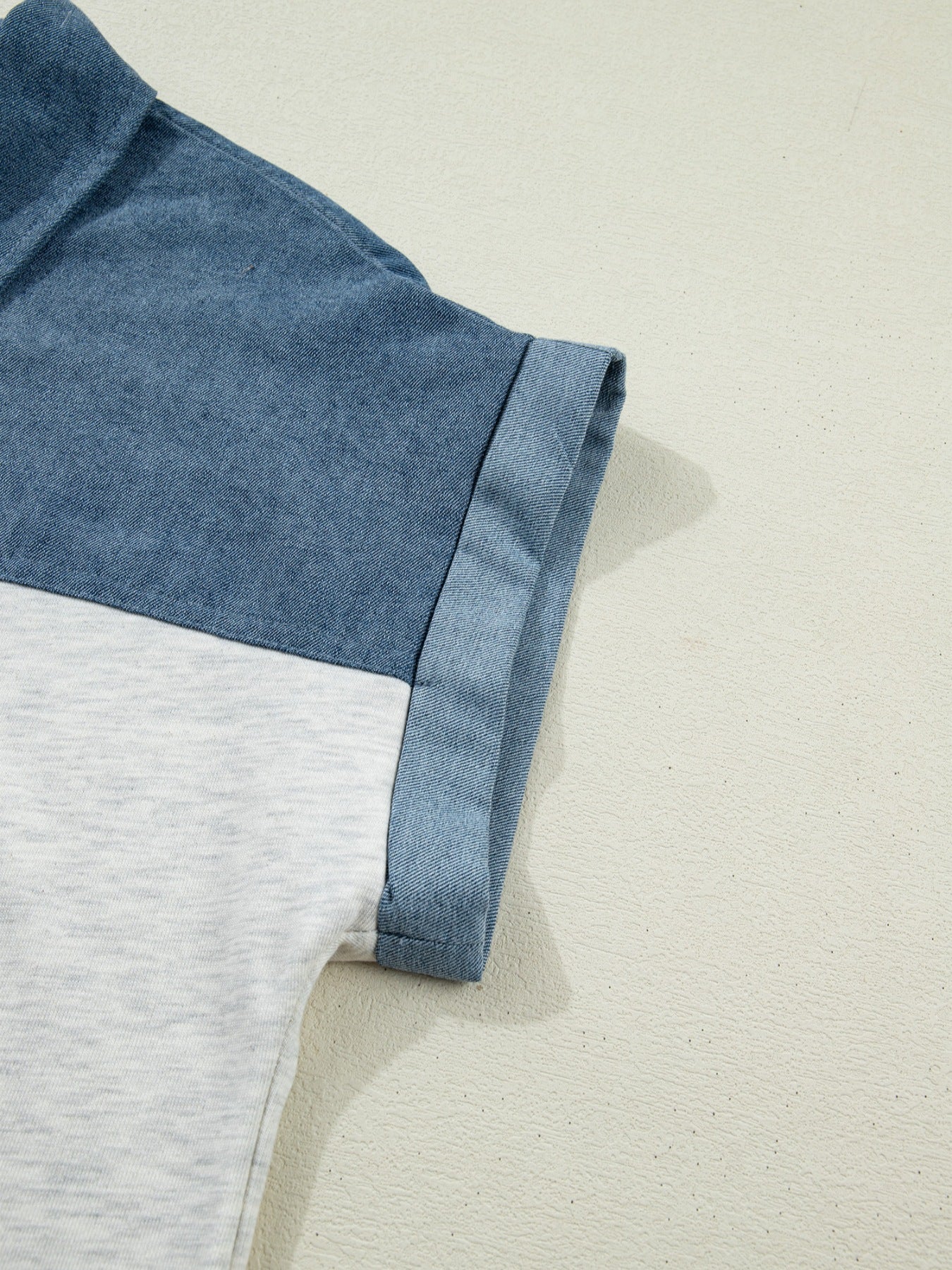 Two-tone denim polo shirt with cuffed sleeves and color-block design.