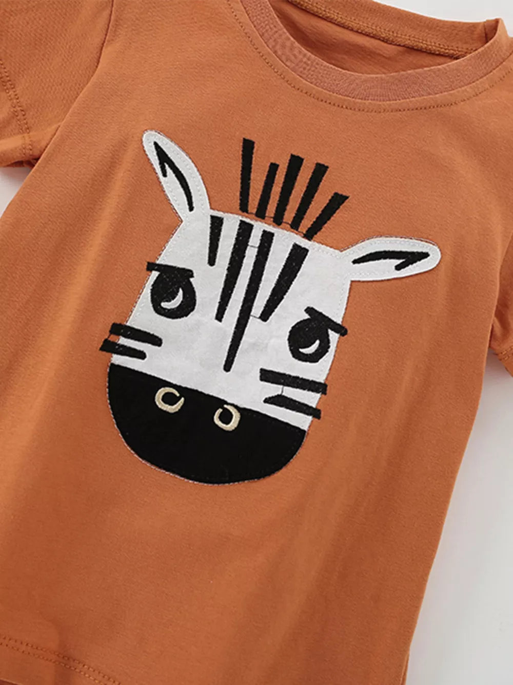 Orange baby tee with a cute zebra face graphic applique.