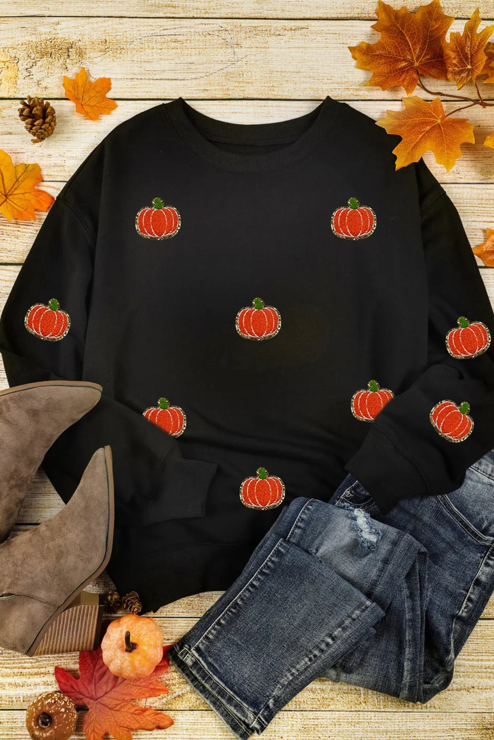 Black crewneck sweatshirt with allover embroidered pumpkins, long sleeves, casual autumn style.